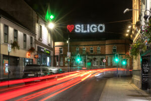 Night photo of O'Connell Street Sligo with the Love Sligo sign lit up and traffic moving in a blur